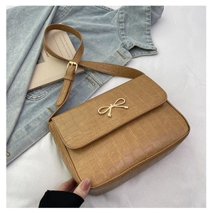 Détail du sac bandoulière caramel à motif crocodile avec nœud doré décoratif