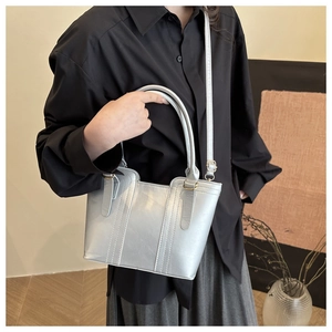 Sac seau métallisé argenté avec finitions dorées porté en bandoulière sur modèle
