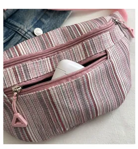 Détail du sac bandoulière à rayures roses avec fermeture éclair et écouteurs sans fil