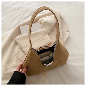 Gros plan d'un sac hobo en daim marron vintage avec fermeture éclair sur un blazer blanc