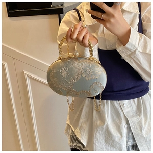 Close-up of light blue spherical evening bag with gold floral embroidery and chain strap