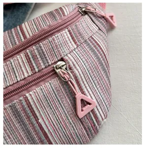 Détail du sac de poitrine en toile à rayures avec fermetures éclair roses et tirettes