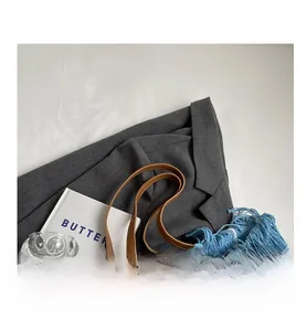Detailed macro view of blue knit tote bag with tassel trim and brown leather handles