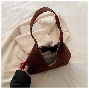 Vue intérieure du sac en daim marron montrant la capacité avec rouge à lèvres et poudre