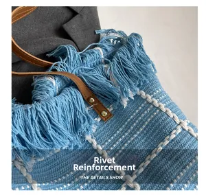 Detail showing blue woven tote bag with fringe edge and brown leather rivet straps