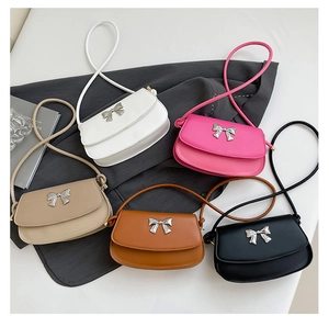Close-up of five minimalist leather shoulder bags featuring elegant silver bow hardware details