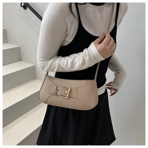 Elegante borsa sottobraccio in pelle beige con fibbia dorata su una modella