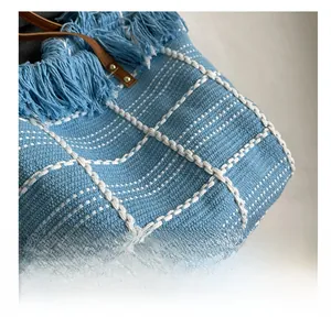 Detailed macro shot of blue checkered knit fabric and soft tassel fringe on a tote bag