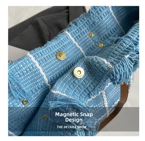 Detail of blue plaid woven tote bag showing functional magnetic buckle and fringe texture