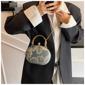 Detail of greyish-blue evening clutch with gold floral relief and metal ring handle