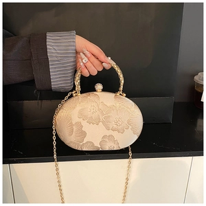 Detailed close-up of champagne silk evening bag with floral embroidery and crystal clasp