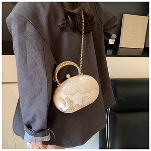 Detail of gold sphere evening bag with floral embossing and pearl clasp handle