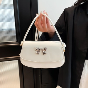 Detailed close-up of a white leather handbag featuring a silver metal bow and chunky handle