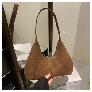 Détail d'un sac hobo en daim marron avec des clous de protection en métal sur le fond
