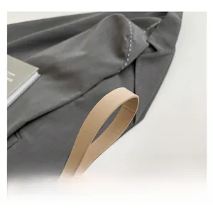 Close-up of beige woven leather bag with flexible handle and adjustable metal buckle
