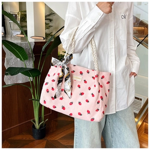 Detail view of pink corduroy strawberry tote bag with woven rope handles and silk scarf deco