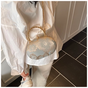 Detail view of mini ball bag with gold floral embroidery and decorative diamond metal handle