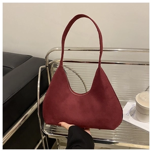 Détail du sac demi-lune en daim bordeaux sur une étagère intérieure élégante