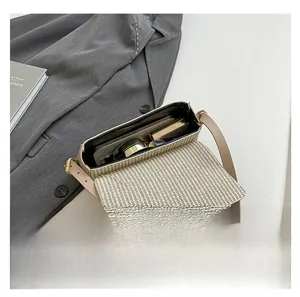 Detail view of woven beige crossbody bag showing interior storage space and phone