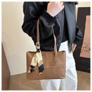 Detailed view of a brown leather tote with crocodile texture and printed silk scarf