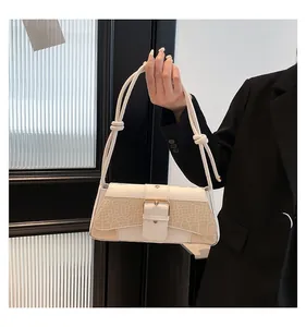 Detail of cream white faux leather shoulder bag with gold buckle and knot handle