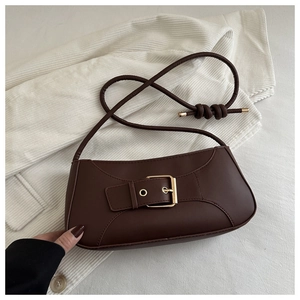 Dettaglio della borsa sottobraccio in pelle marrone scuro con fibbia dorata e cinturino