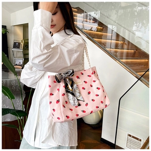 Detail of pink corduroy strawberry tote bag with fashion tag and silk scarf handle