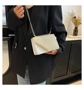 Detail view of off-white crossbody bag with woven texture and gold chain strap