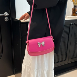 Close-up of vibrant pink crossbody bag with decorative silver metal bow detail