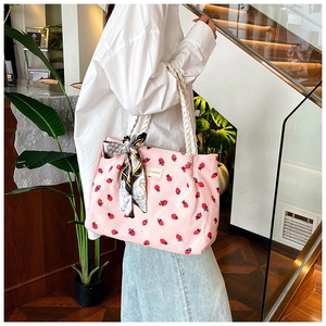 Pink corduroy tote bag with strawberry print and white rope handles shown in use
