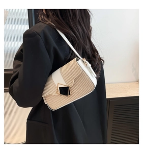 Detail of minimalist straw woven shoulder bag with white leather trim and gold buckle