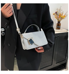 Detail van een zilveren metallic handtas met gouden gesp en verstelbare schouderriem