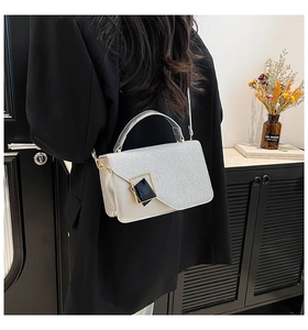 Detalle del bolso bandolera de purpurina con hebilla metálica en un entorno de estilo