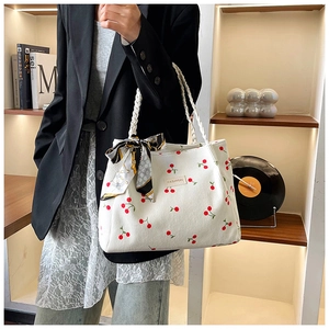 Detail of white corduroy tote bag with cherry prints and a decorative silk scarf