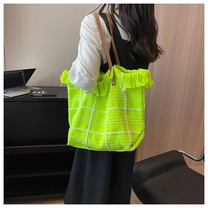 Detail of neon green woven tote bag featuring white checkered pattern and fringe trim
