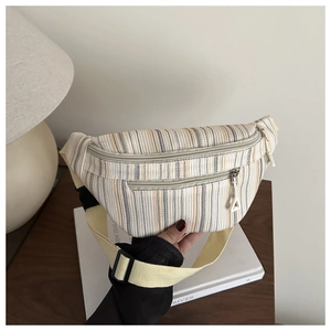 Détail du sac de poitrine en toile rayée avec double fermeture éclair et sangle jaune