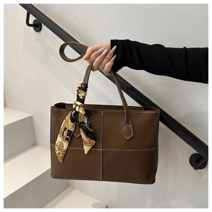Brown tote bag detail with snake pattern texture, contrast stitching and silk scarf
