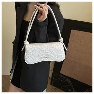 Detail of white woven baguette bag with golden text and knot decorative handle
