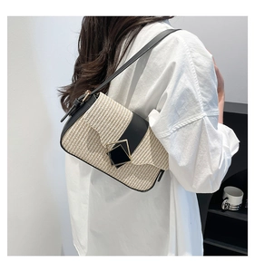 Detail of a beige straw woven bag with black leather trim and gold diamond buckle