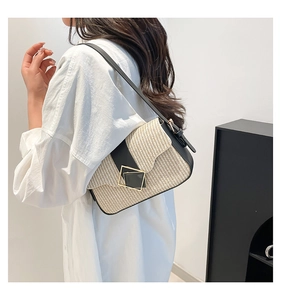 Detail of a chic woven shoulder bag with black leather trim and golden square buckle