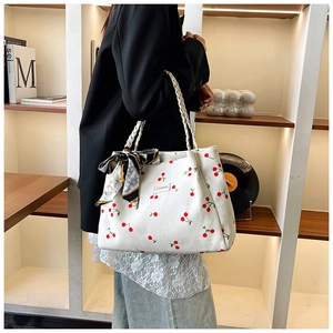 Detail of white corduroy tote bag with red cherry print and decorative silk scarf strap
