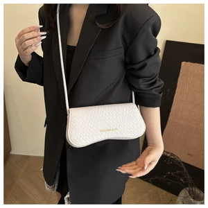 Detail of white faux leather crossbody bag with snake texture and gold printed text