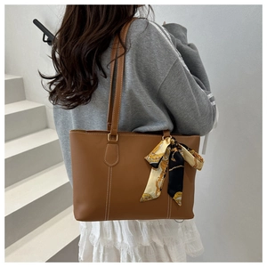 Detail of caramel brown tote bag with contrast stitching and silk scarf accessory