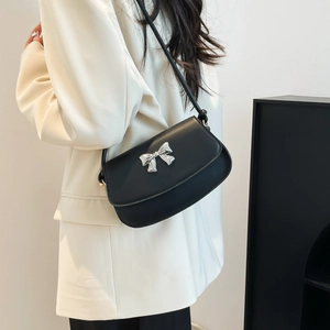 Close-up of black leather underarm bag featuring a metallic silver bow decoration