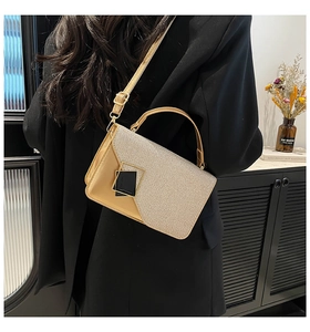 Detalle de bolso bandolera con purpurina dorada llevado con un elegante blazer negro