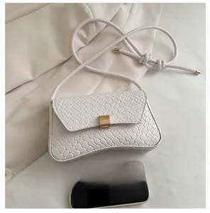 Close-up of white woven underarm bag featuring a golden metal buckle and texture