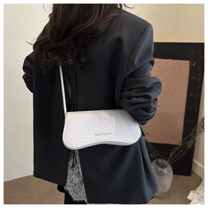 Detailed view of woven leather texture on a white shoulder bag with gold hardware