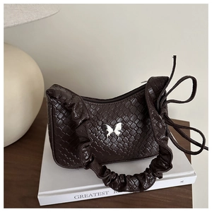 Détail d'un sac marron café à texture tressée avec boucle papillon argentée et volants