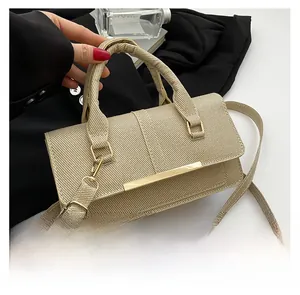 Detail showing the textured fabric surface and golden metal bar on the beige square bag