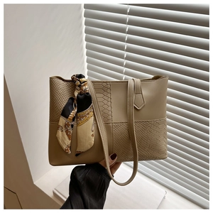 Detail of khaki tote bag featuring smooth faux leather and snakeskin texture with silk scarf